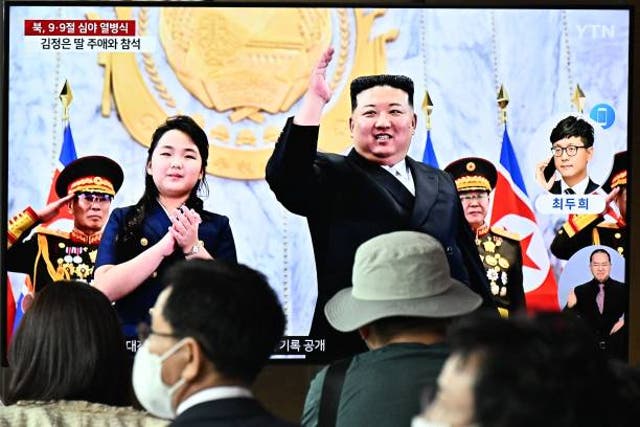 <p>People sit in front of a television showing a news broadcast with a photo of North Korea’s leader Kim Jong Un and his daughter attending a parade marking the 75th anniversary of the country’s founding, at a railway station in Seoul on 9 September 2023</p>
