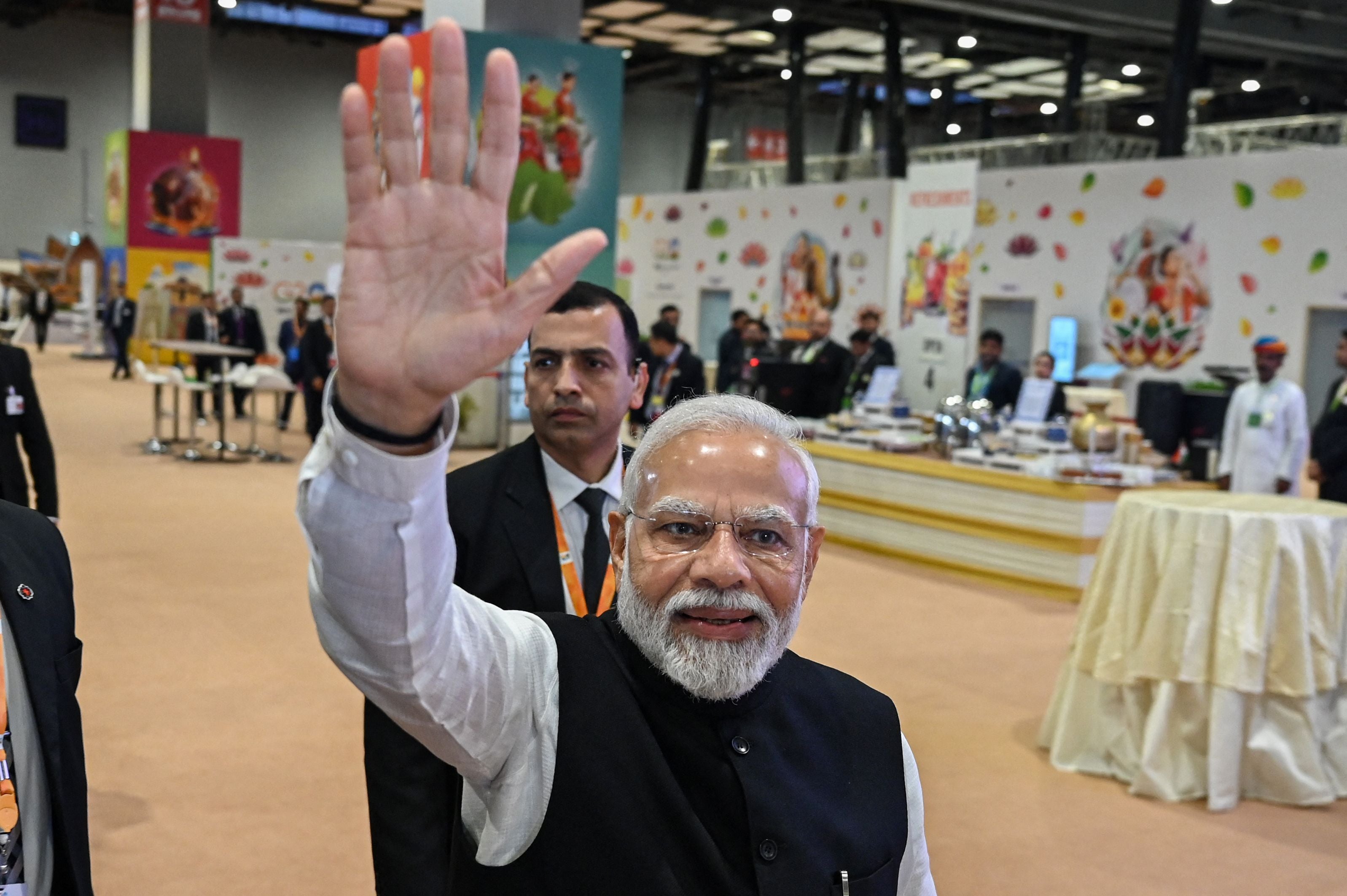 India's Prime Minister Narendra Modi (C) waves to the media during his visit to the International media centre, at the G20 summit venue