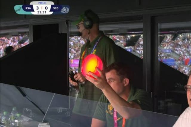 <p>South Africa assistant coach Felix Jones holds up different coloured  lights during the game </p>