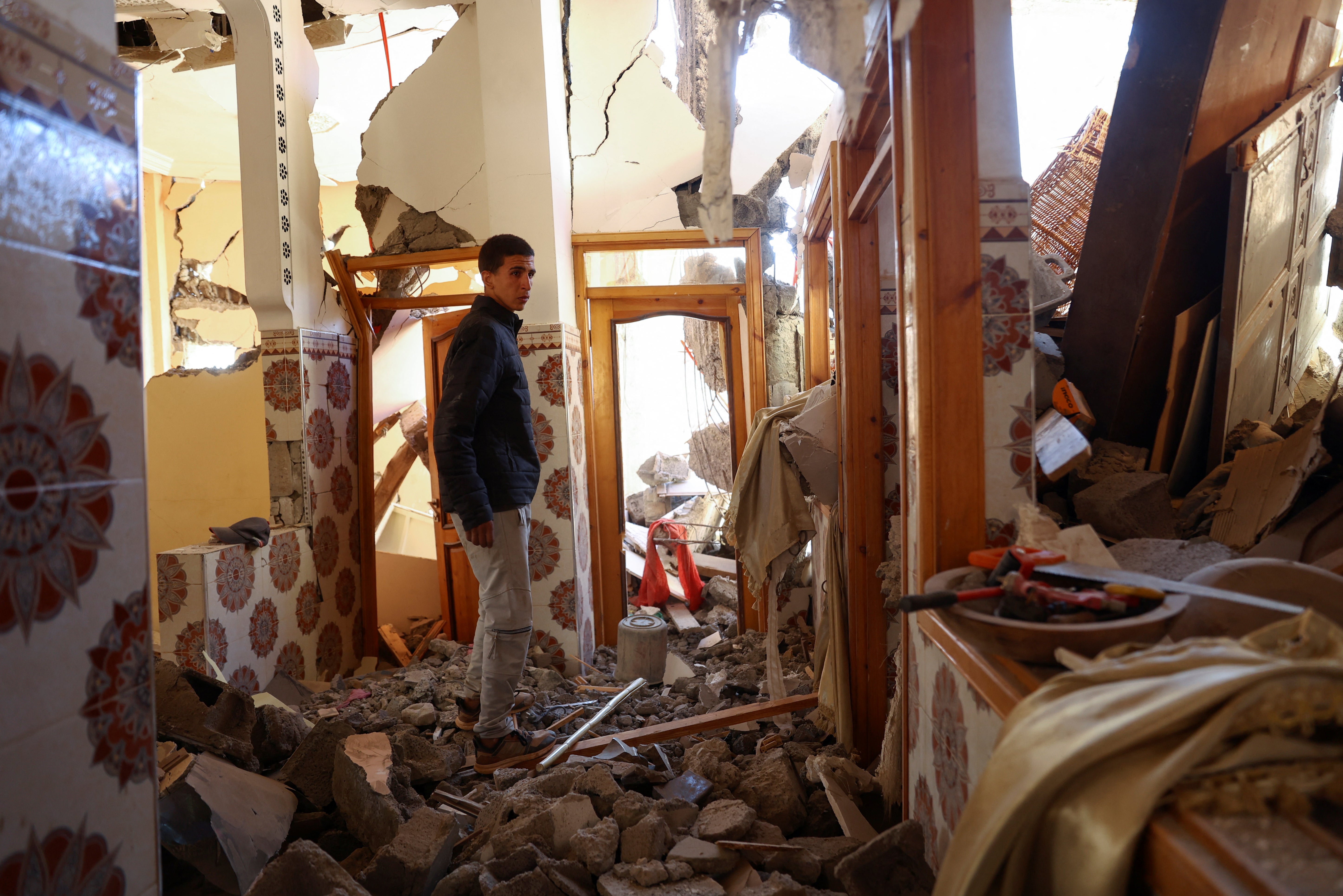 Mouath Aytnasr, 20, walks on the rubble of his damaged house, on the outskirts of Talat N’Yaaqoub