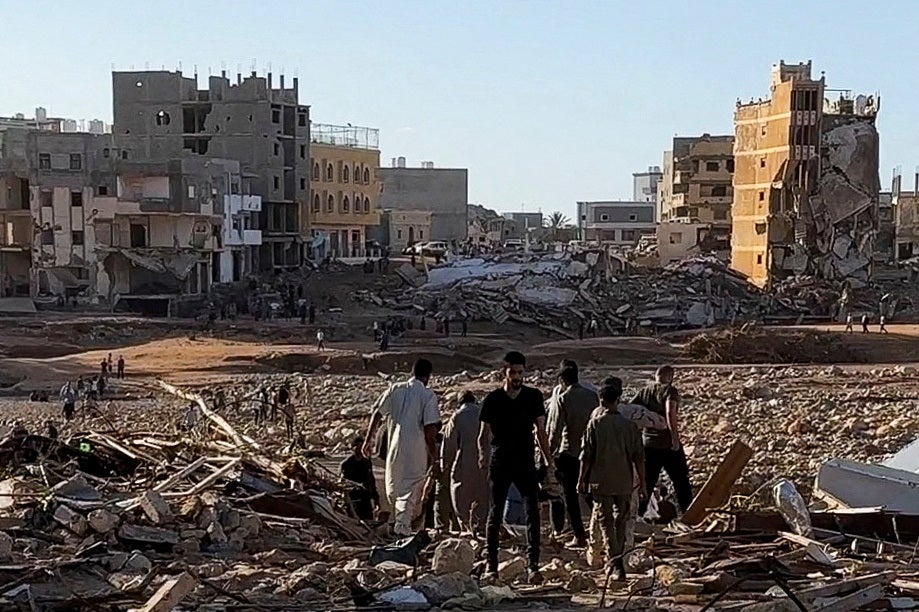 People walk through debris after a powerful storm and heavy rainfall hit Libya, in Derna, Libya