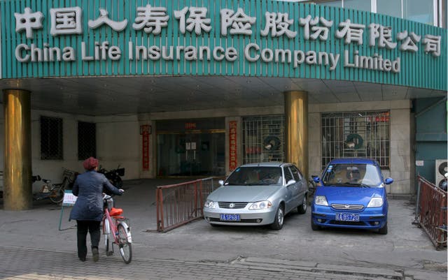 <p>File: A woman walks past a branch of China Life Insurance in Shenyan</p>