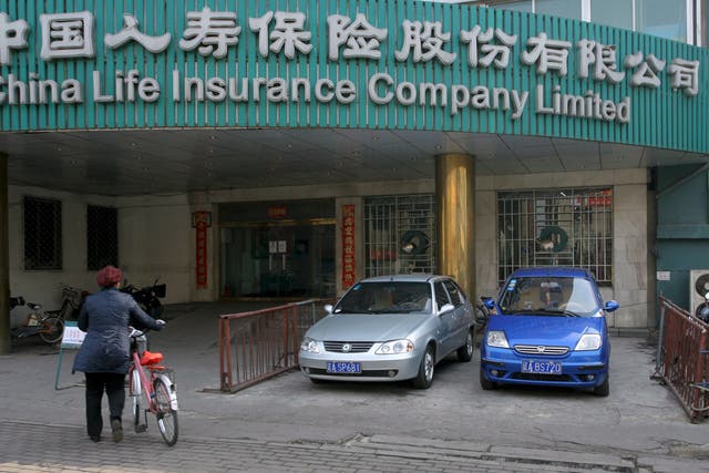 <p>File: A woman walks past a branch of China Life Insurance in Shenyan</p>