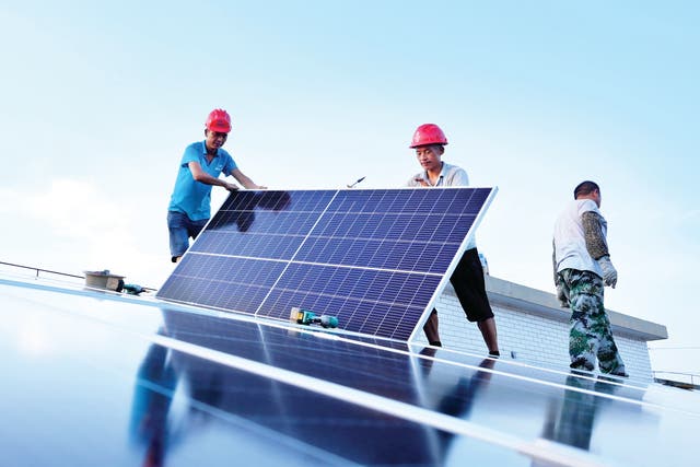 <p>Workers instal solar panels on the roof of an energy cube that was built to provide electricity for residents of Nanjing, Jiangsu province </p>