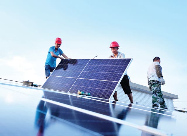 <p>Workers instal solar panels on the roof of an energy cube that was built to provide electricity for residents of Nanjing, Jiangsu province </p>