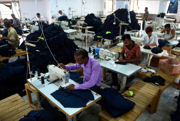 File: Pakistani workers stitch cloths at a garment factory in Karachi on 15 July 2019