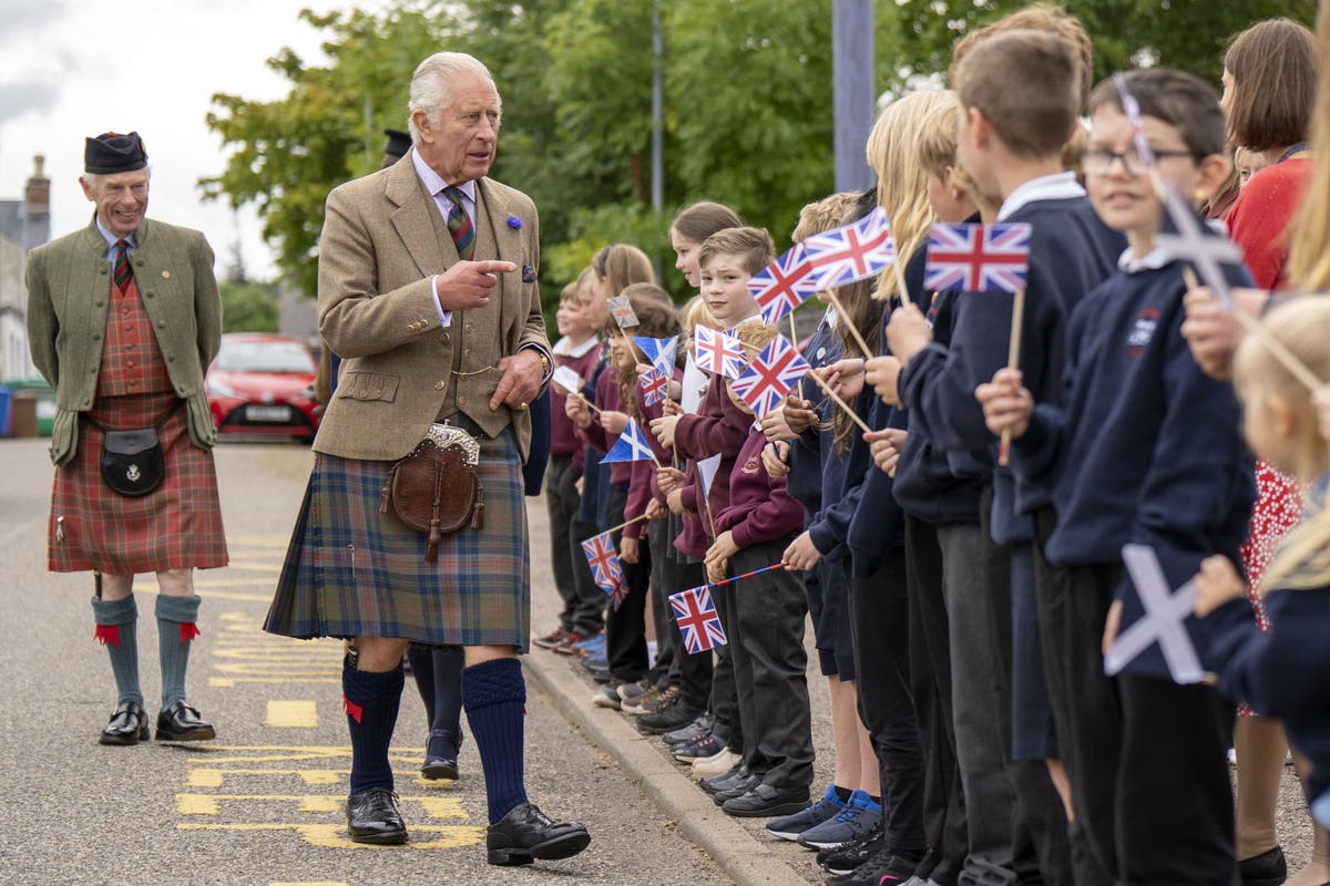 King wears new tartan and greets well-wishers in French on village visit