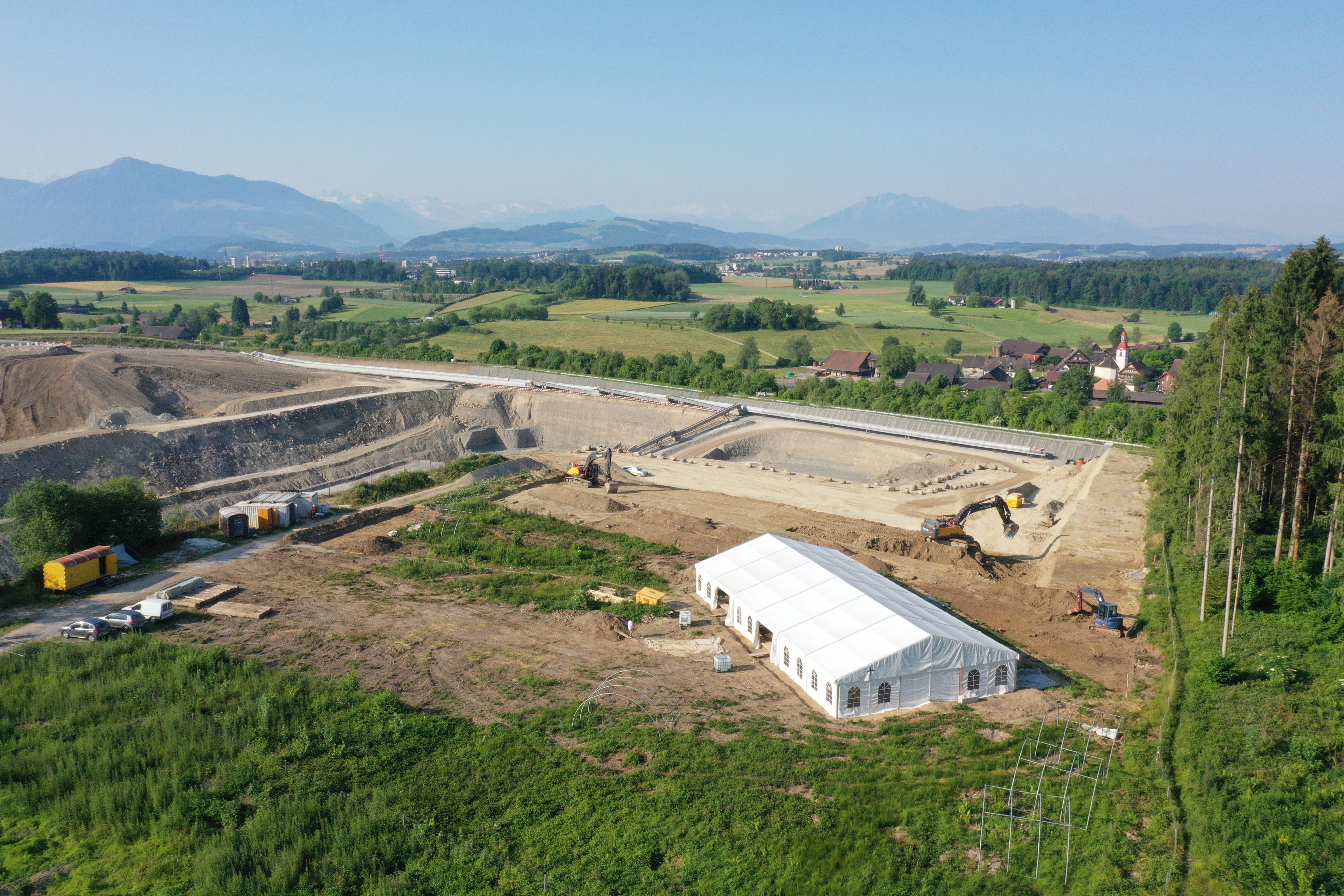 Aerial view of the current excavation in Cham-?bnetwald with a view of the Alps. Under the tent is a part of the Roman building.