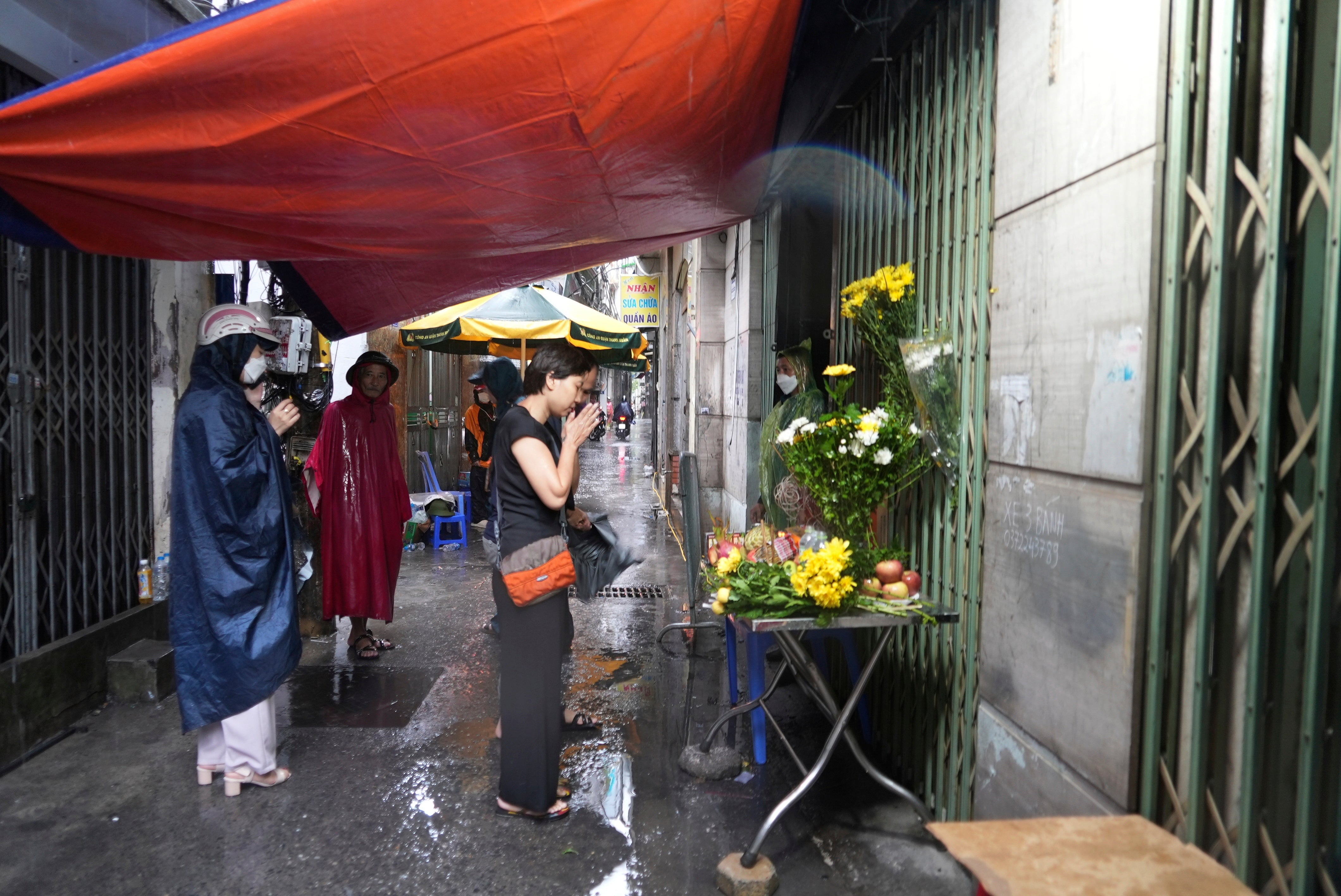 People pray in front of a makeshift shrine set up in front of a building that was caught on fire in Hanoi