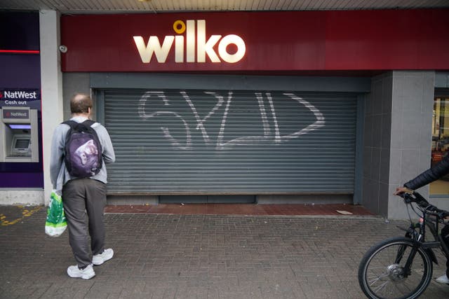 A man watches the shutter come down on the final day of trading at the Wilko store in Barking, east Londom (Yui Mok/PA)