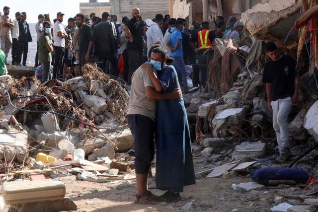 <p>Two men comfort each other in the devastated Libyan city of Derna</p>