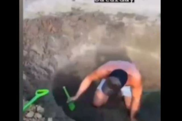 <p>Still from footage of men digging hole</p>
