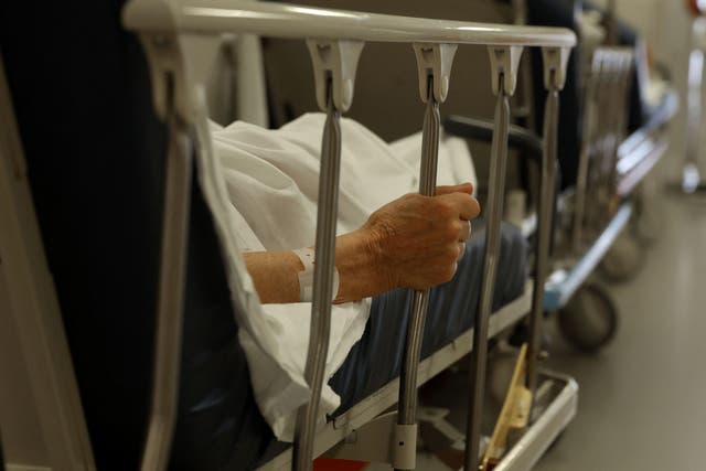 <p>A patient clutches the bars of his bed with his hand as he waits for treatment in the corridor of the emergency service at The Arcachon Hospital in Arcachon, south-western France on 10 August 2023</p>