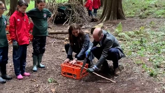 <p>Prince William chops wood and Kate hides in a den as they join school children getting back to nature.</p>
