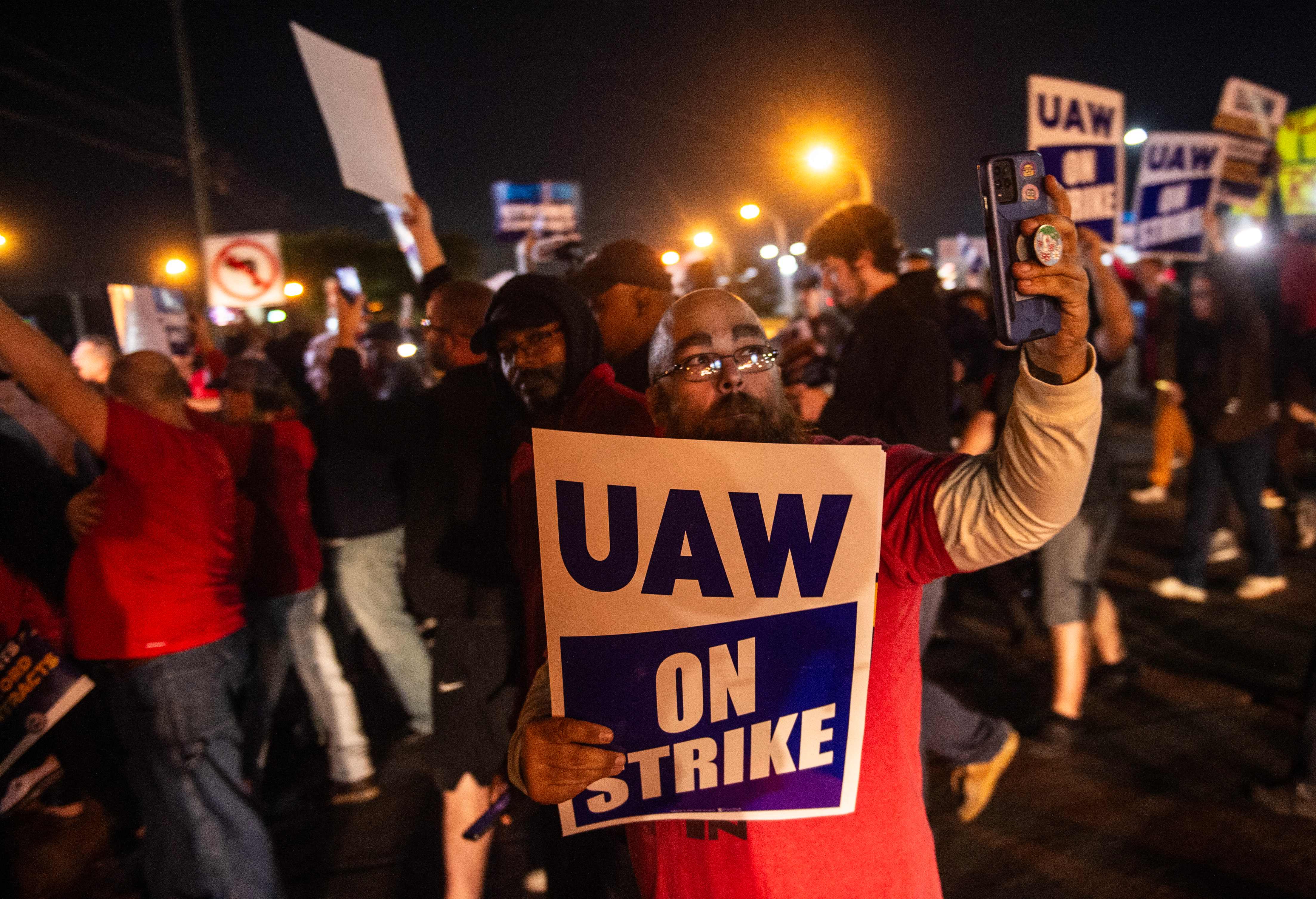 Members of theUnited Auto Workers picket and hold signs outside of the UAW Local 900 headquarters across the street from the Ford Assembly Plant in Wayne, Michigan on 15 September.