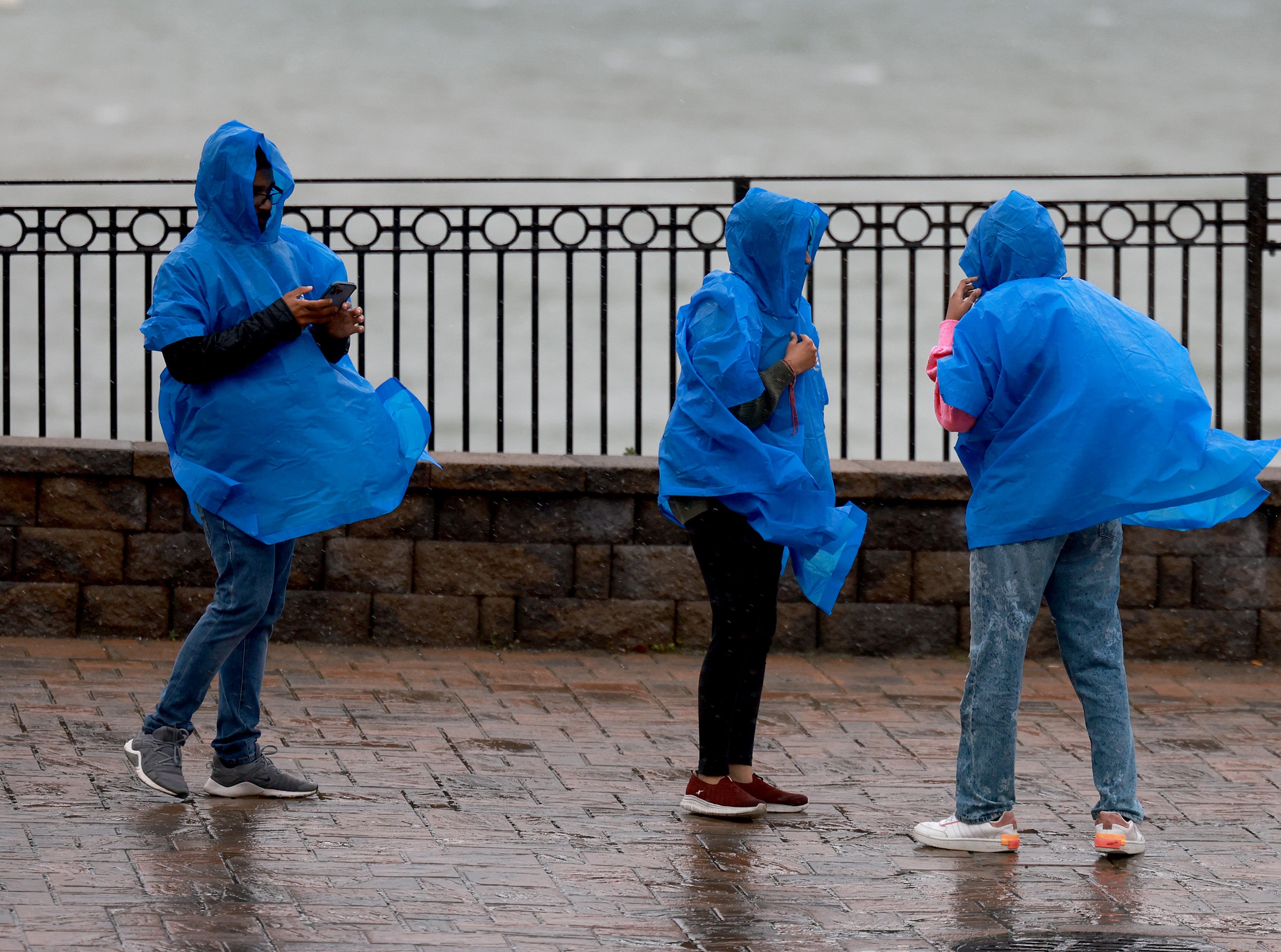 People walk in the rain and wind from Post-Tropical Cyclone Lee
