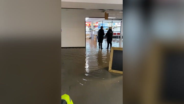 Inside a flooded Exeter Airport as staff and passengers wade through water in terminal