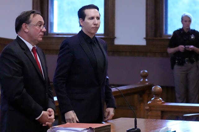 <p>Musical artist Marilyn Manson, whose legal name is Brian Hugh Warner, center, stands with his attorney </p>