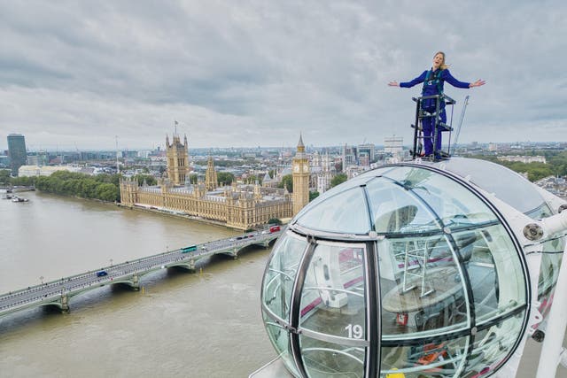 Sally Williams harnessed 135m (443ft) high on top of the London Eye for 20 minutes at 7am presenting the weather forecast (ITV News London/PA)