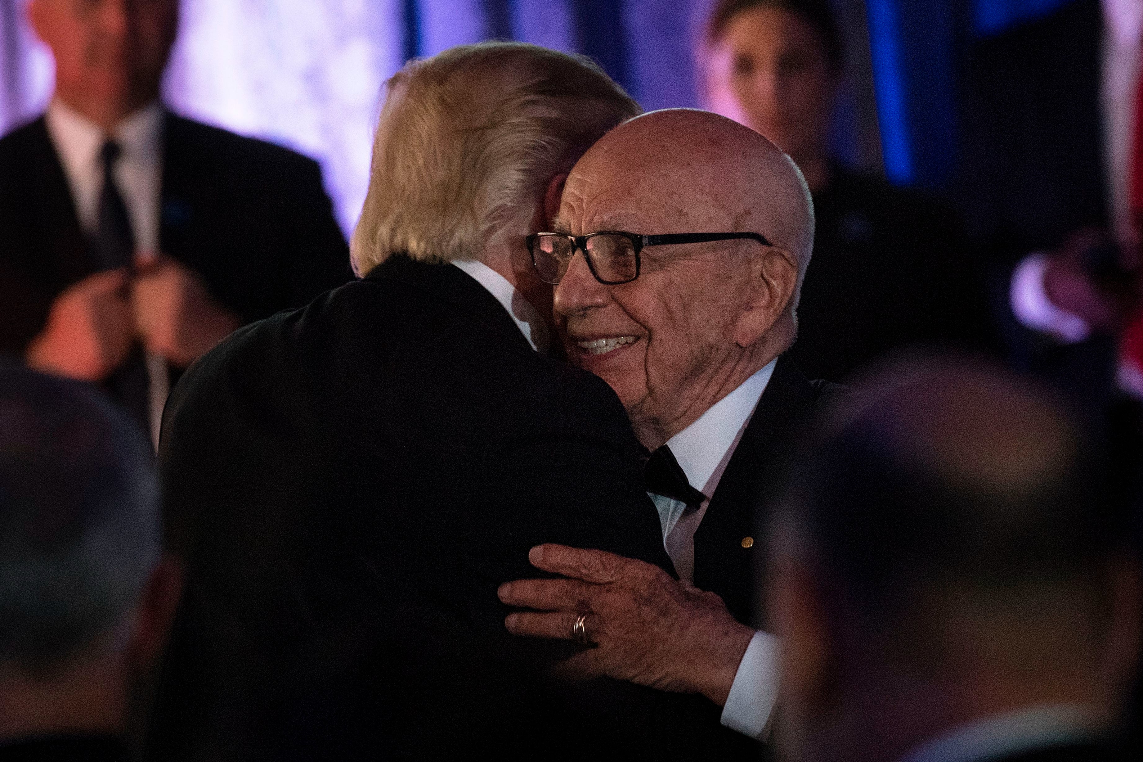 US President Donald Trump (L) is embraced by Rupert Murdoch, Executive Chairman of News Corp, during a dinner to commemorate the 75th anniversary of the Battle of the Coral Sea during WWII