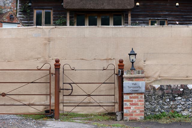 <p>A sign saying ‘Pub Temporarily Closed’ and a large brown security fence outside The Crown Inn pub owned by Russell Brand's company, in Pishill, Oxfordshire </p>