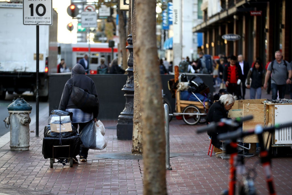 <p>A homeless man pulls a cart with his belongings in San Francisco, California</p>