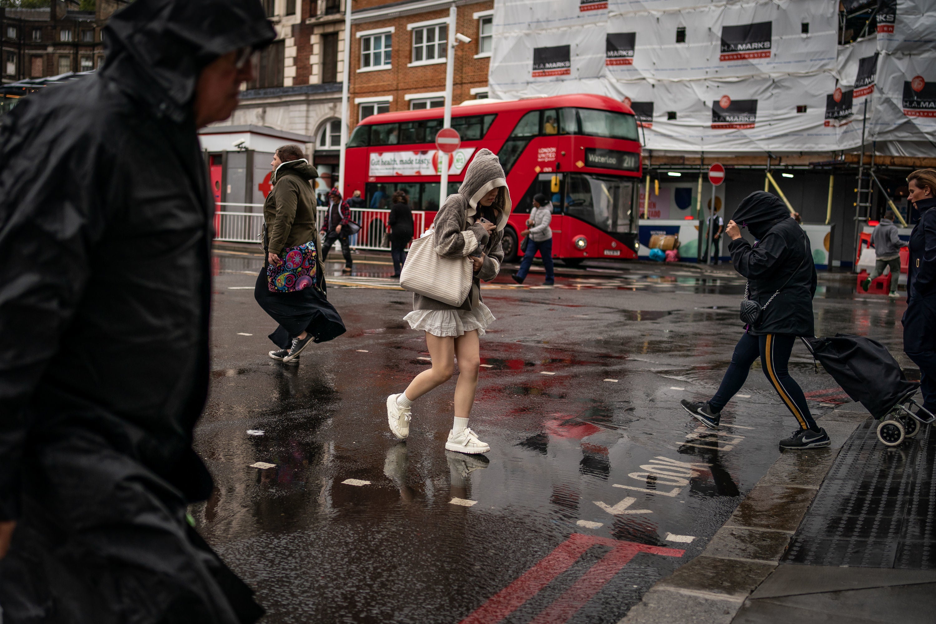 People walk through wet weather in Victoria, London.