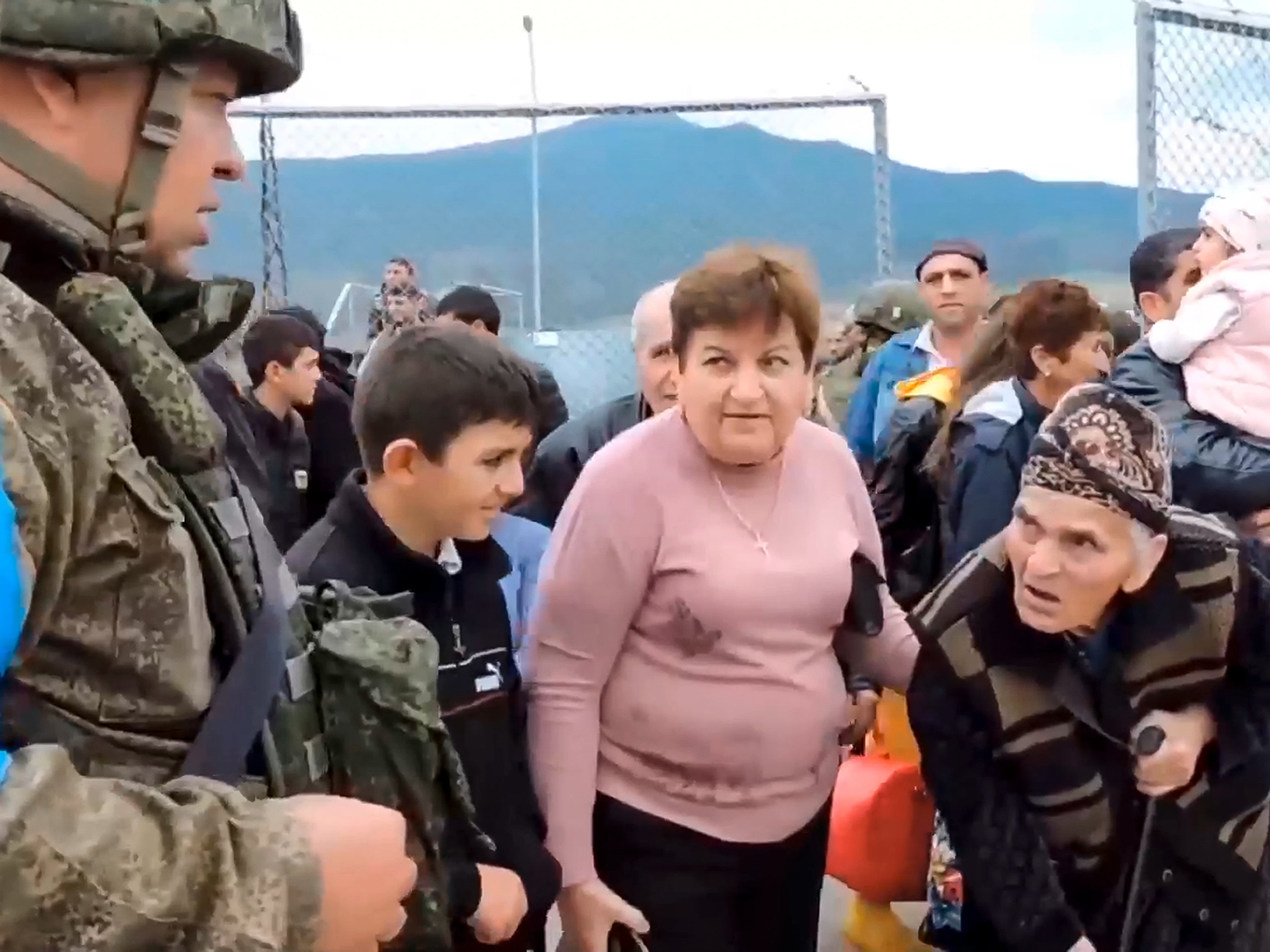 Ethnic Armenians enter a camp near Stepanakert in Nagorno-Karabakh on Thursday as a Russian military peacekeeper looks on