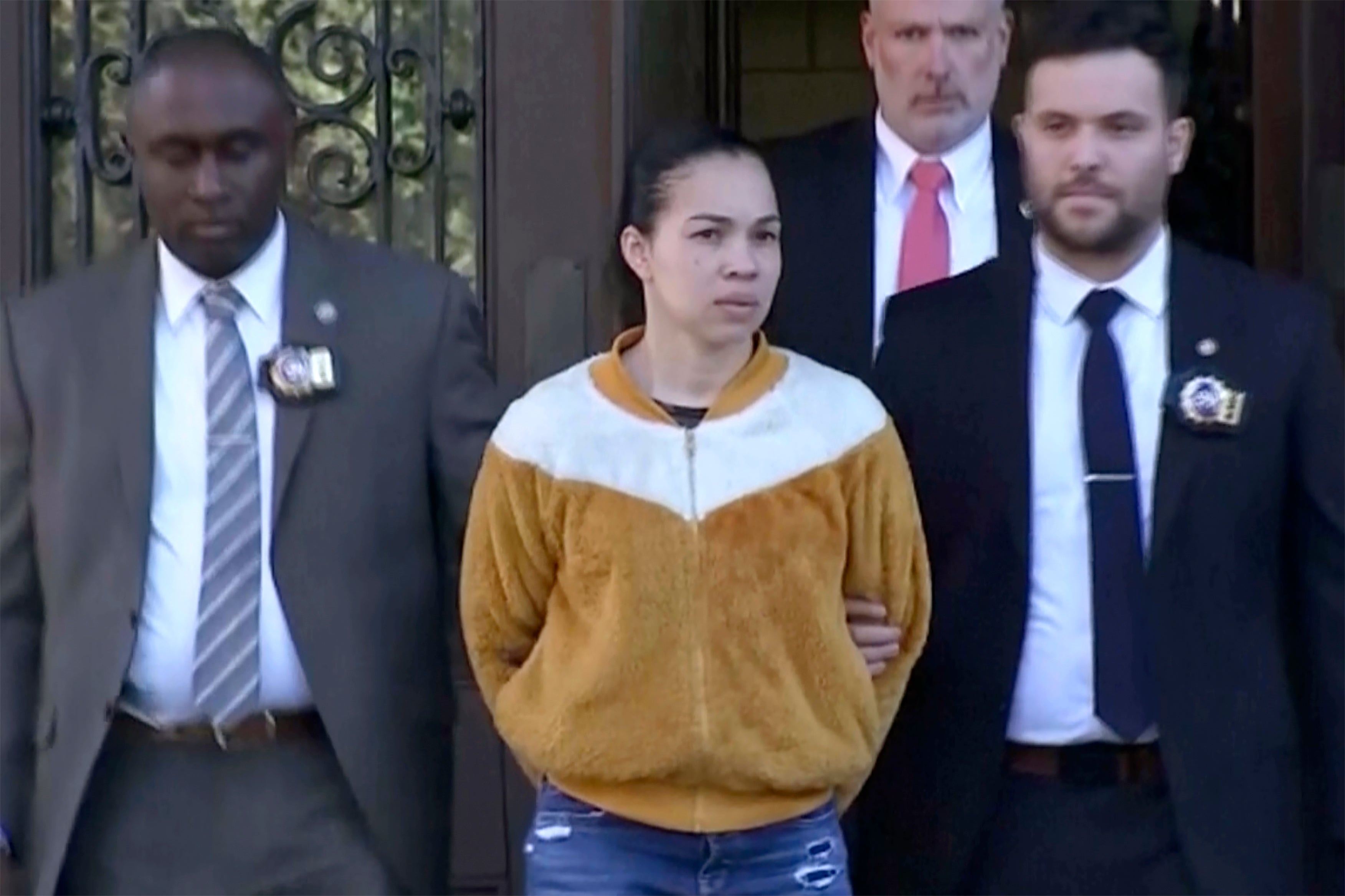 Grei Mendez, centre, is escorted by law enforcement personnel from a New York Police station