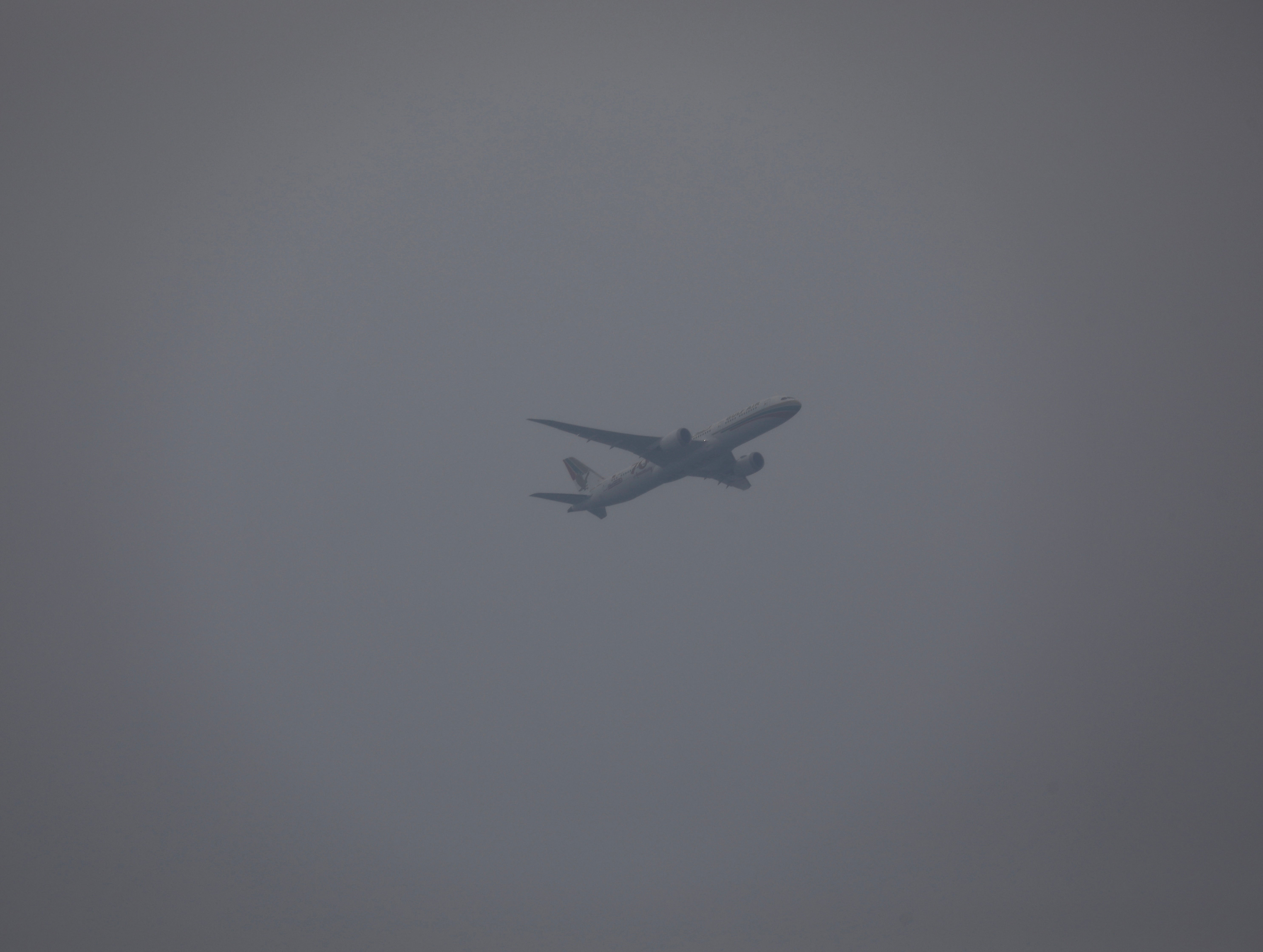 An airplane flies on a sky shrouded with smog in Taguig city, Philippines