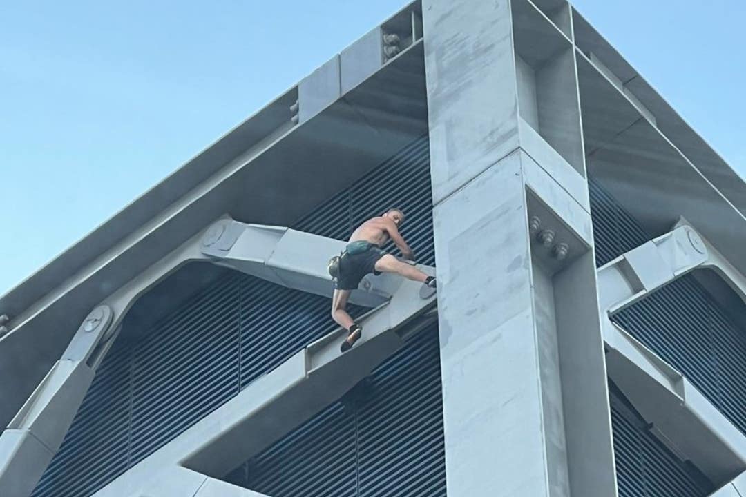 A shirtless man climbing the Cheesegrater in London