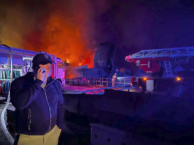 <p>Governor of Sevastopol Mikhail Razvozhaev talks on the phone as flames rise from the main headquarters of Russia’s Black Sea Fleet in an attack earlier this month </p>