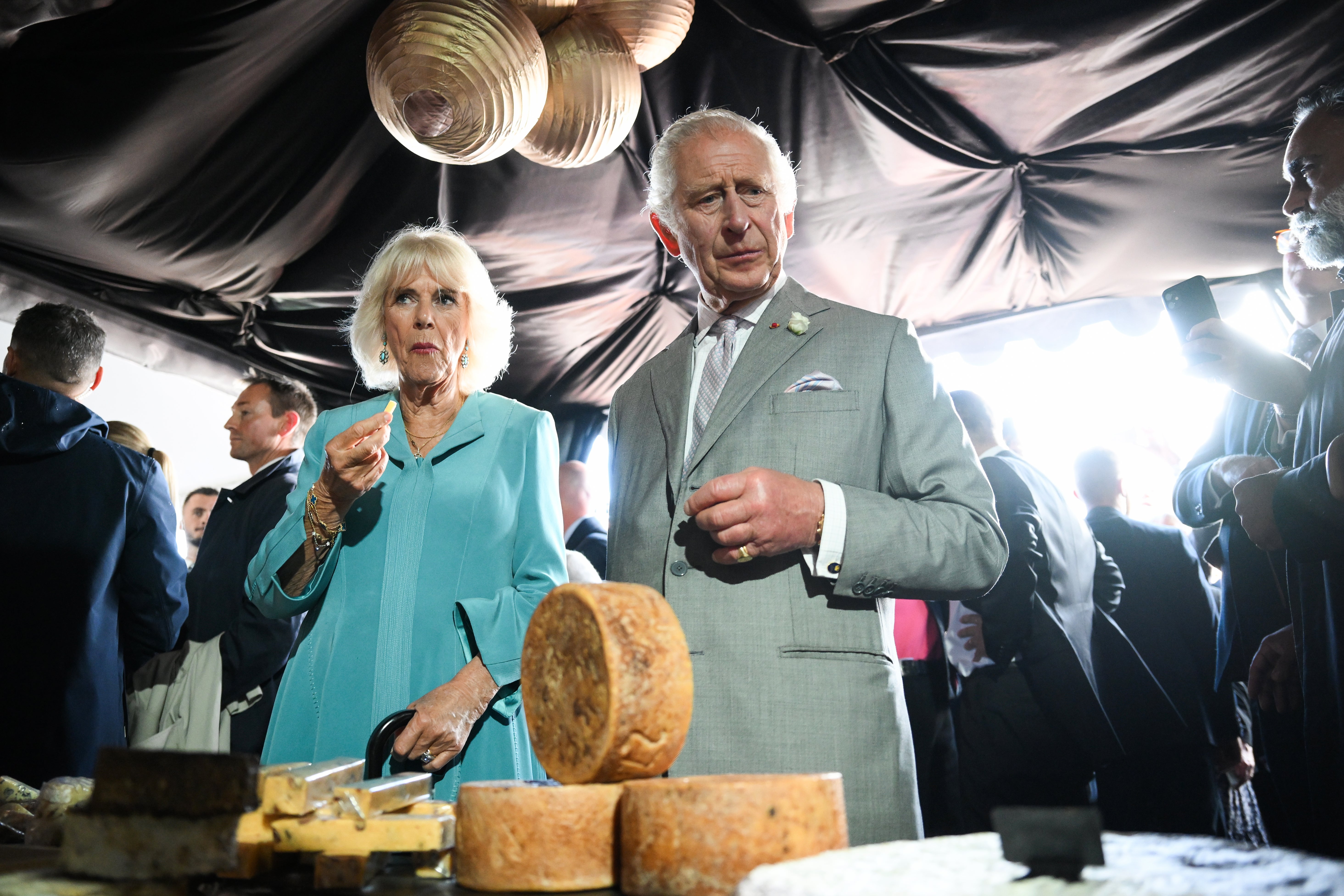 The King and Queen sampling cheese at a festival-style event showcasing the best of British and French local produce