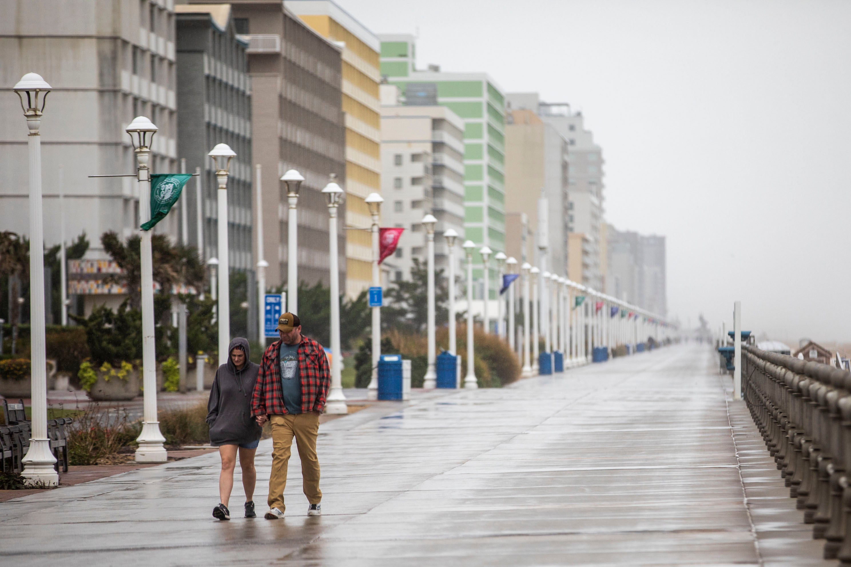 Beach-goers brave the weather and walk along the boardwalk at the Virginia Beach Oceanfront on Friday, Sept. 22
