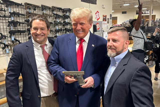 <p>Donald Trump poses with a pistol in a gun shop in South Carolina that he visited with Georgia congresswoman Marjorie Taylor Greene</p>