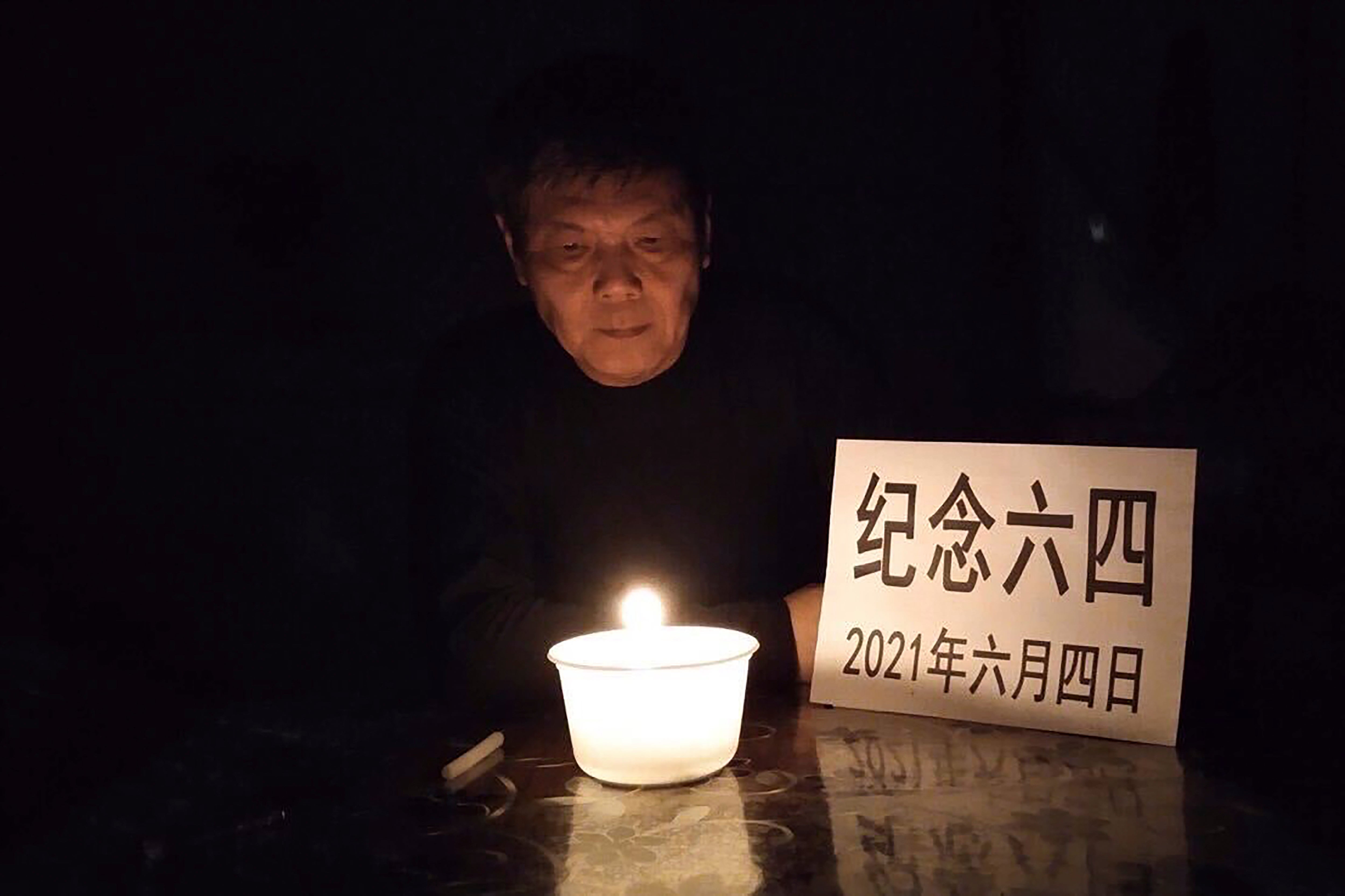 In this photo taken June 4, 2021 and released by Chen Siming, he poses for photos with a paper which reads ‘Commemorate June 4, on 2021, June 4’ near a candle light in Zhuzhou in central China’s Hunan province. The Chinese dissident is known for regularly commemorating the 4 June 1989 crackdown on pro-democracy protesters in Beijing’s Tiananmen Square