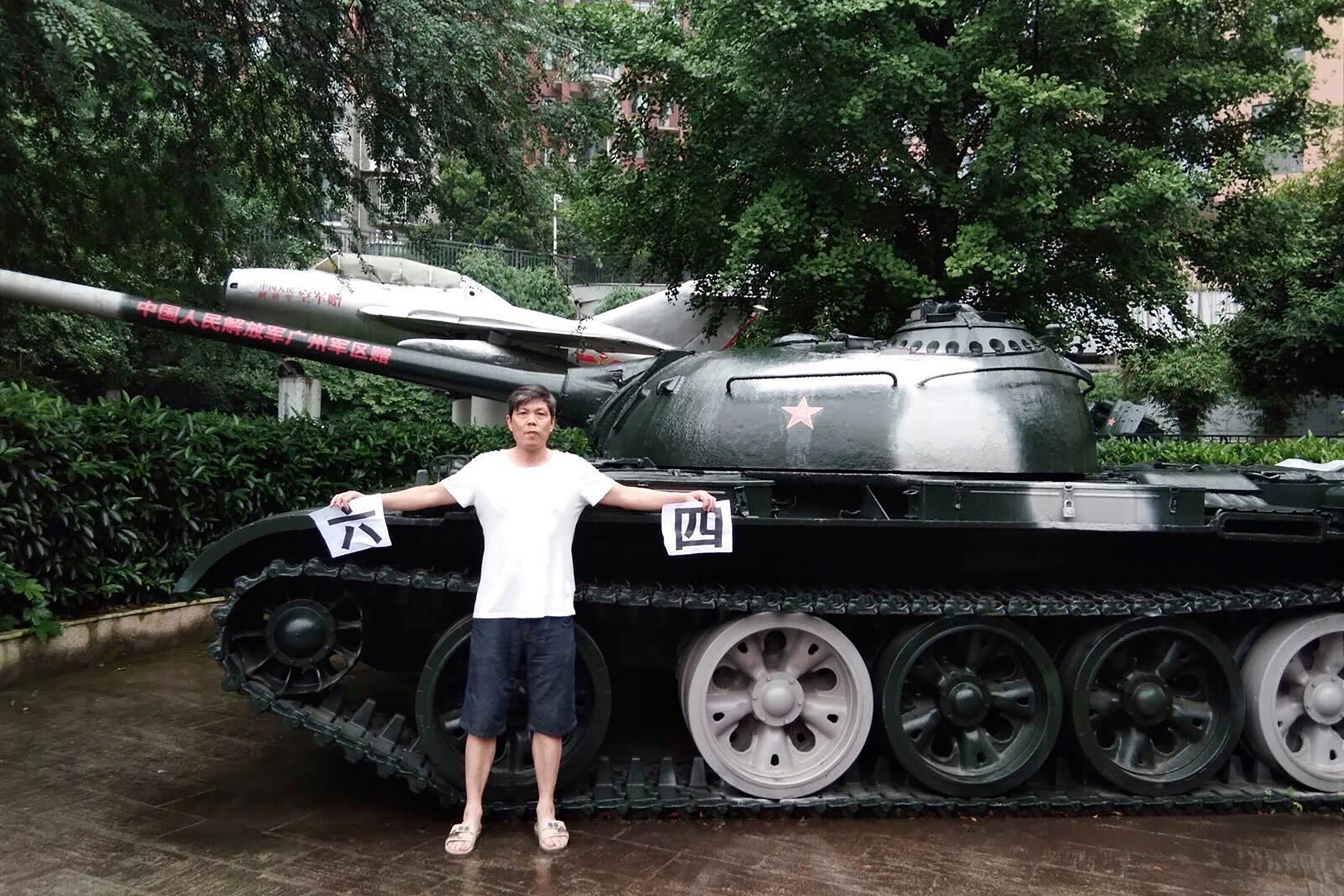 In this photo taken on 4 June 2018 by Chen Siming, he holds up pieces of paper with the Chinese characters for 6 and 4 referring to 4 June next to a display of an obsolete tank in Zhuzhou in central China’s Hunan province