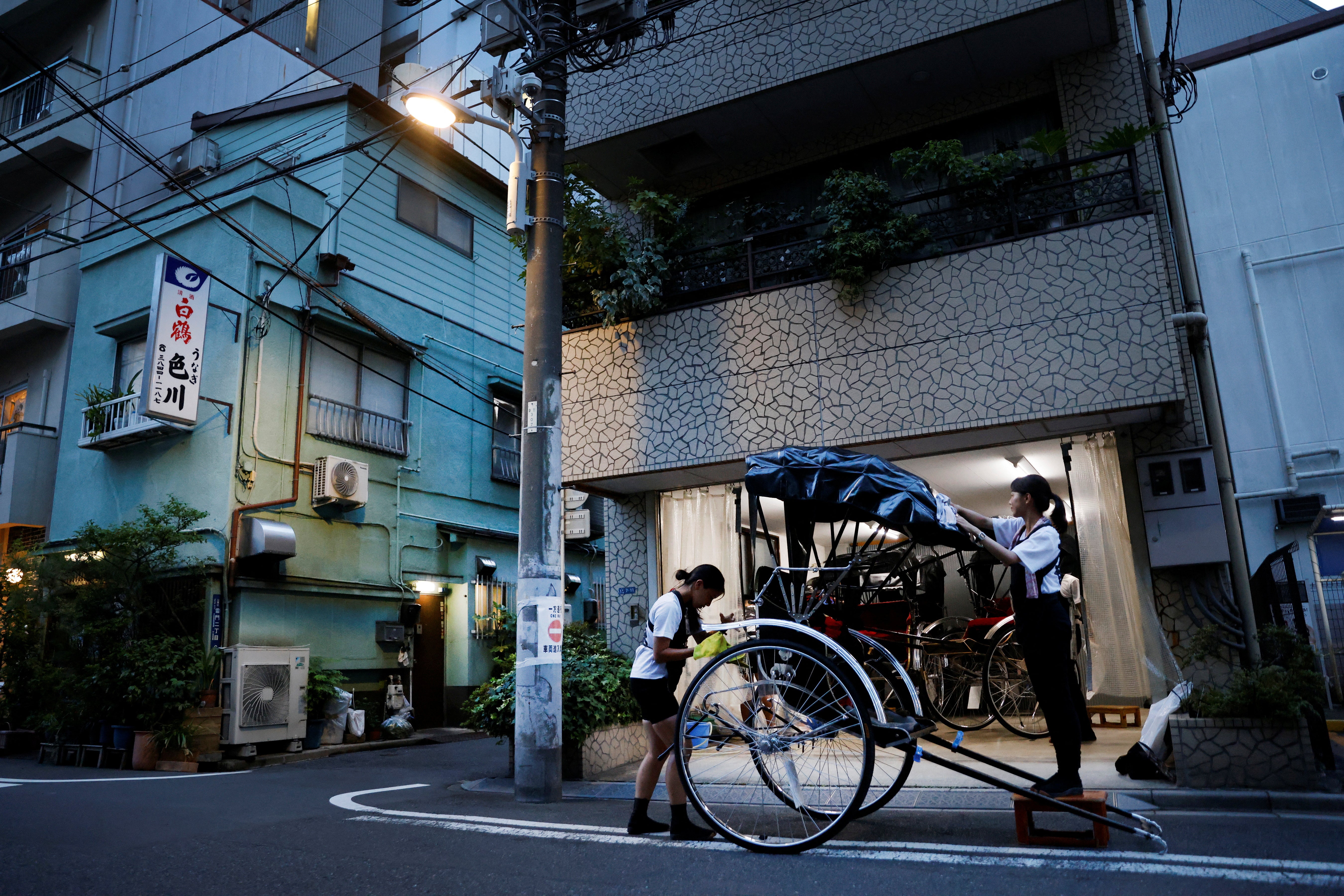 Drivers Akina Suzuki (left), 19, and Misato Otoshi, 30, clean up a rickshaw after work