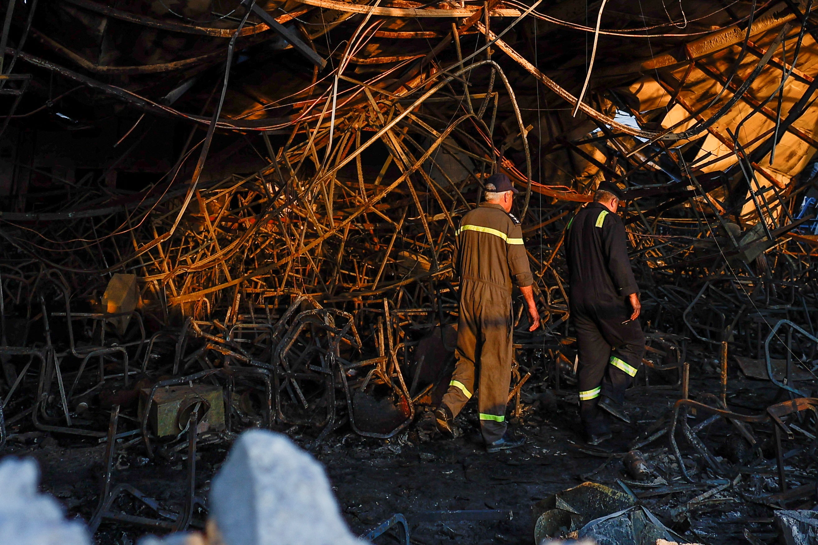<p>Officials walk through the rubble at the site following a fatal fire at a wedding celebration, in the district of Hamdaniya in Iraq's Nineveh province, Iraq</p>