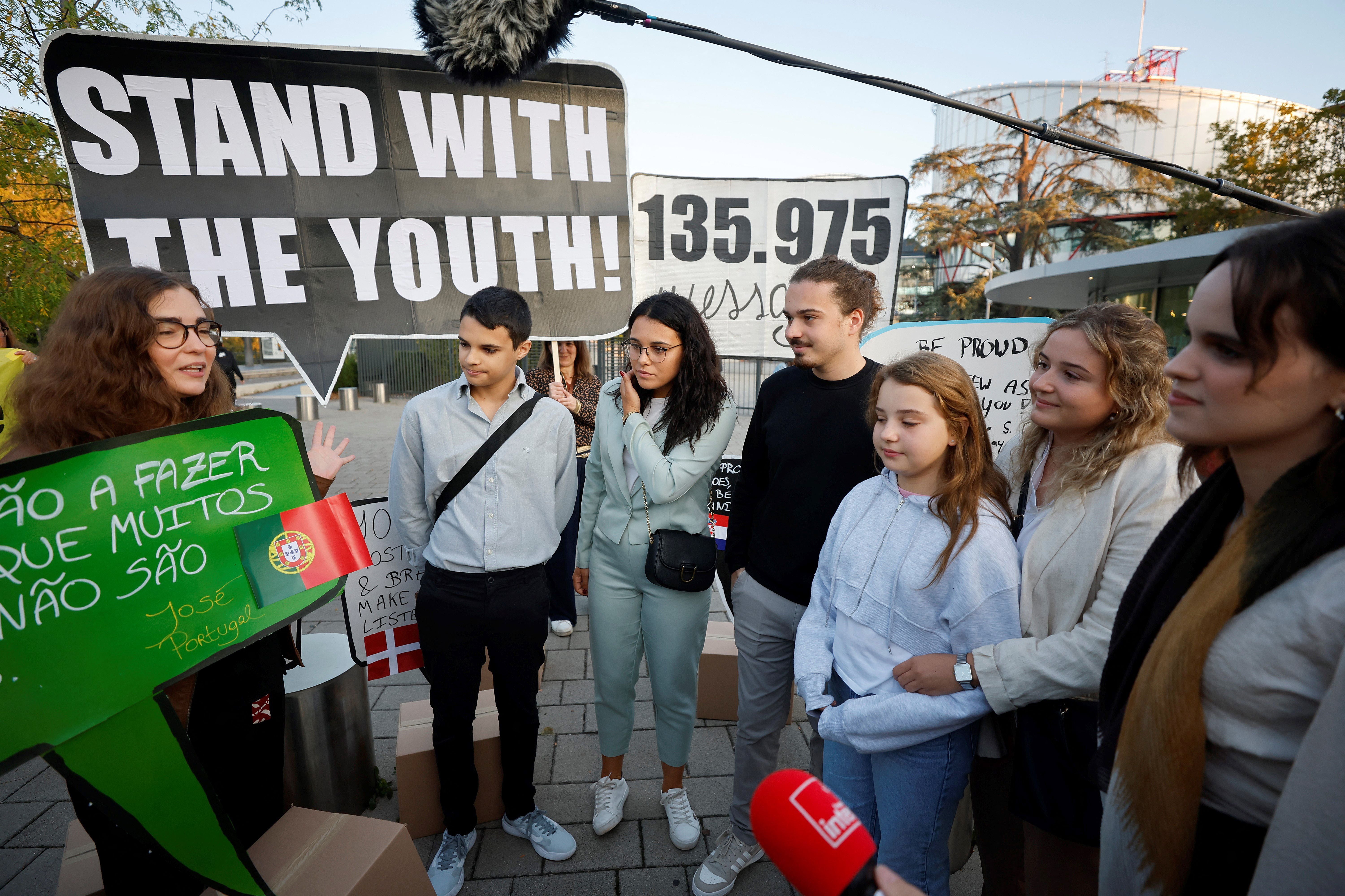 Young Portuguese citizens hold placards as they arrive at the European Court of Human Rights (ECHR) for a hearing in a climate change case involving themselves against 32 countries, in Strasbourg, eastern France