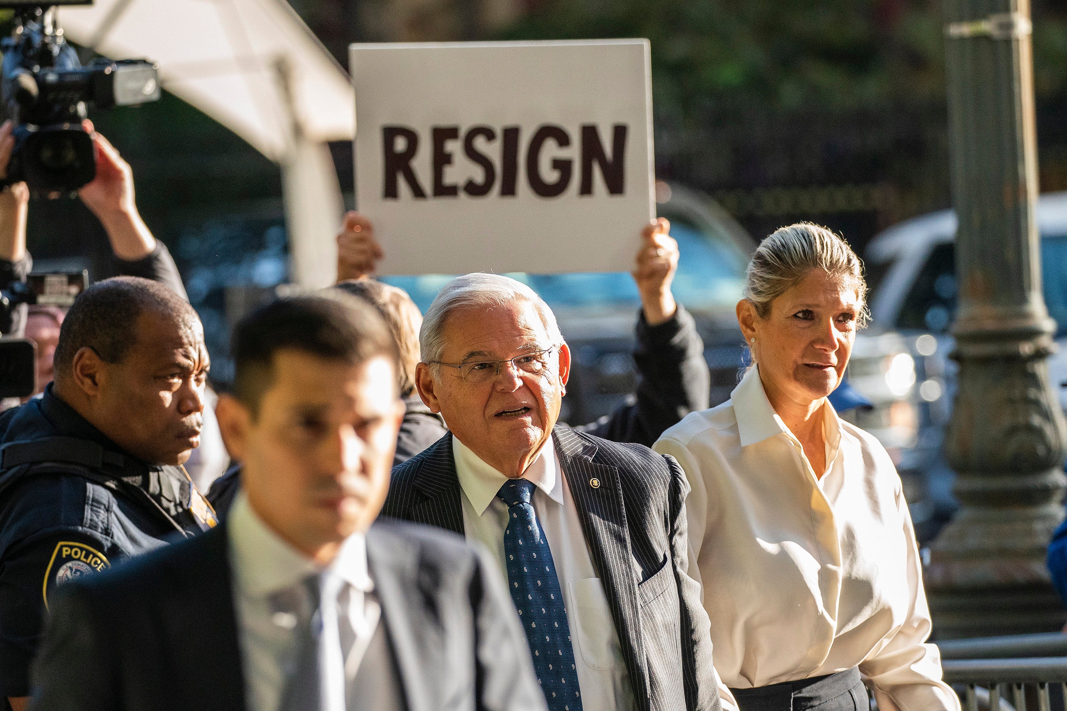 A protester holds a sign calling for US Senator Robert Menendez to resign as he enters federal court in New York City on 27 September.