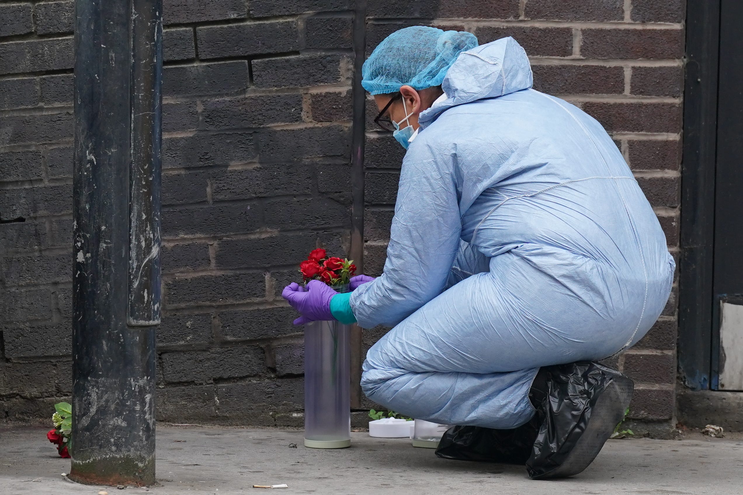 A forensic investigator puts flowers into a container at the scene near the Whitgift shopping centre