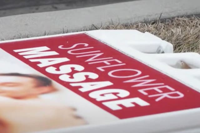 <p>A sign for Sunflower Massage in American Fork, Utah, lying on the ground after police raided the business on suspicion that illegal sex services were being offered by workers</p>