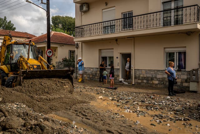 <p>Local residents stand on a muddy street after the Storm Elias, in Volos </p>