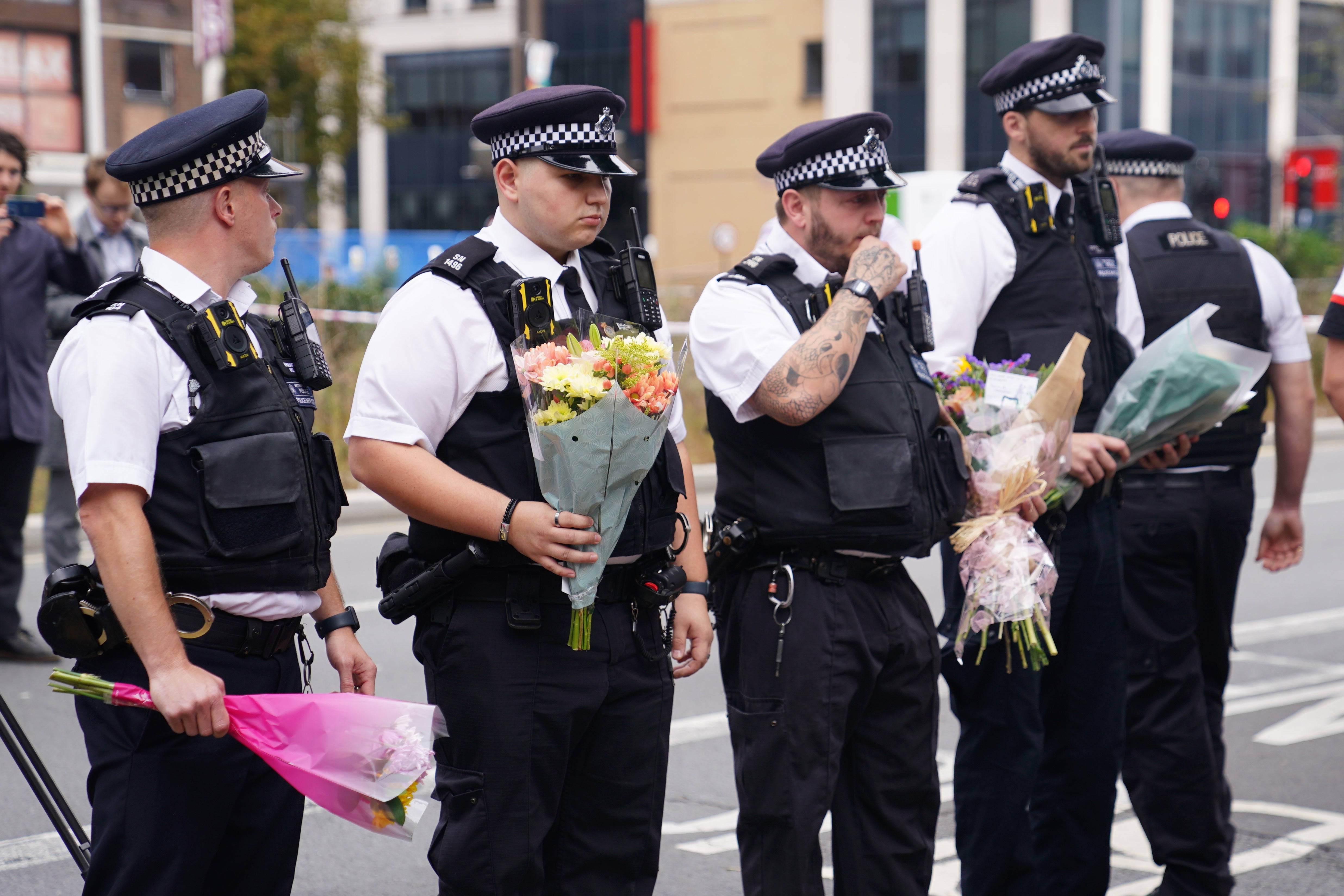 Police officers lay flowers at the scene in Croydon
