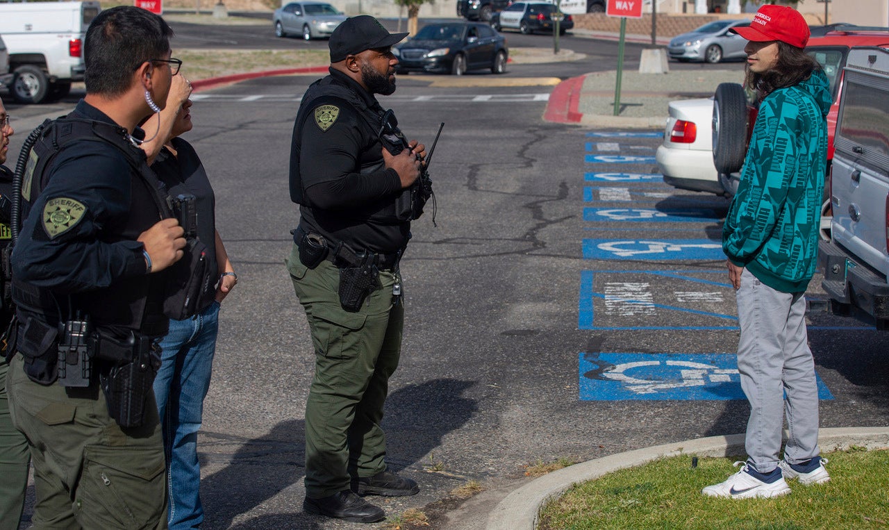 Ryan Martinez, right, talks with law enforcement before violence erupted as activists protested a postponed installation of a statue of Spanish conquistador Juan de Onate