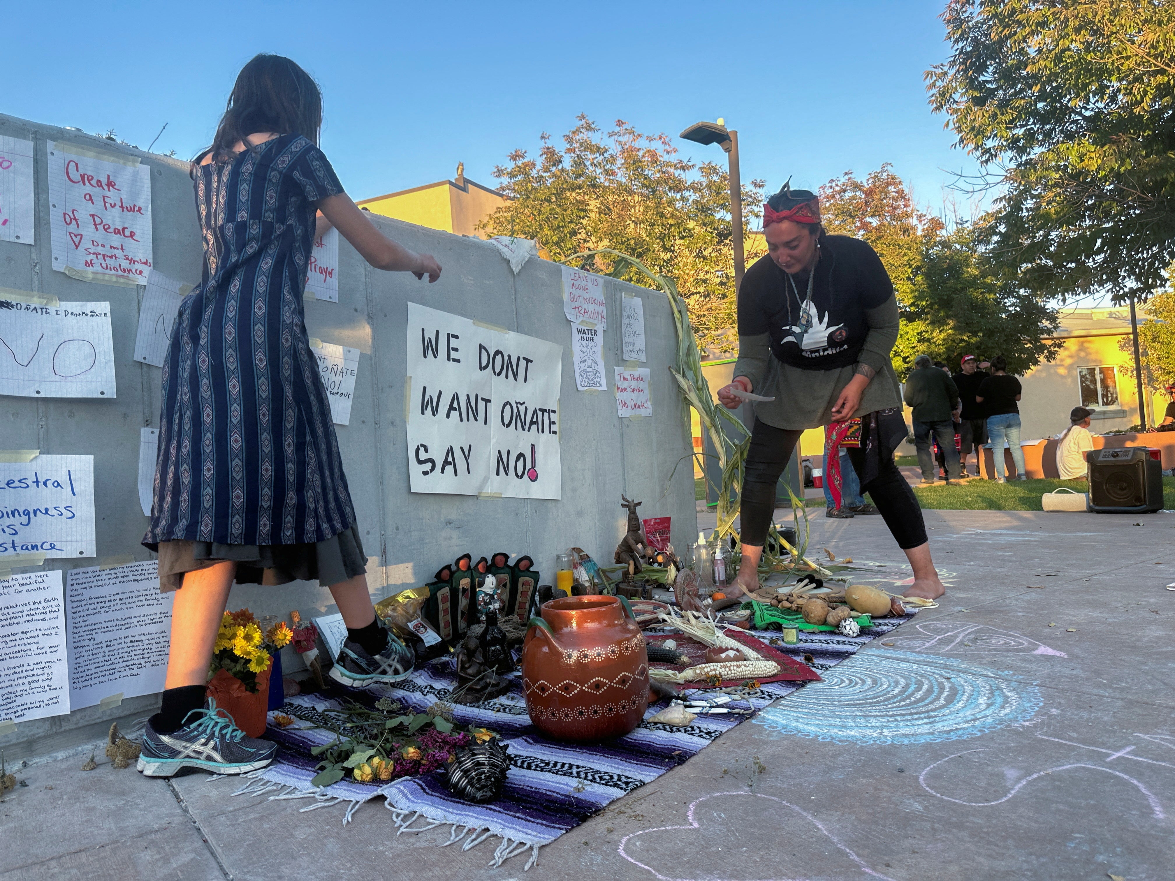 Ixchel Topete and her mother Soula Topete arrange an altar in front of a concrete platform where authorities had planned to reinstall a statue of conquistador Juan de Onate but postponed the event after protests, at the Rio Arriba County Complex in Espanola