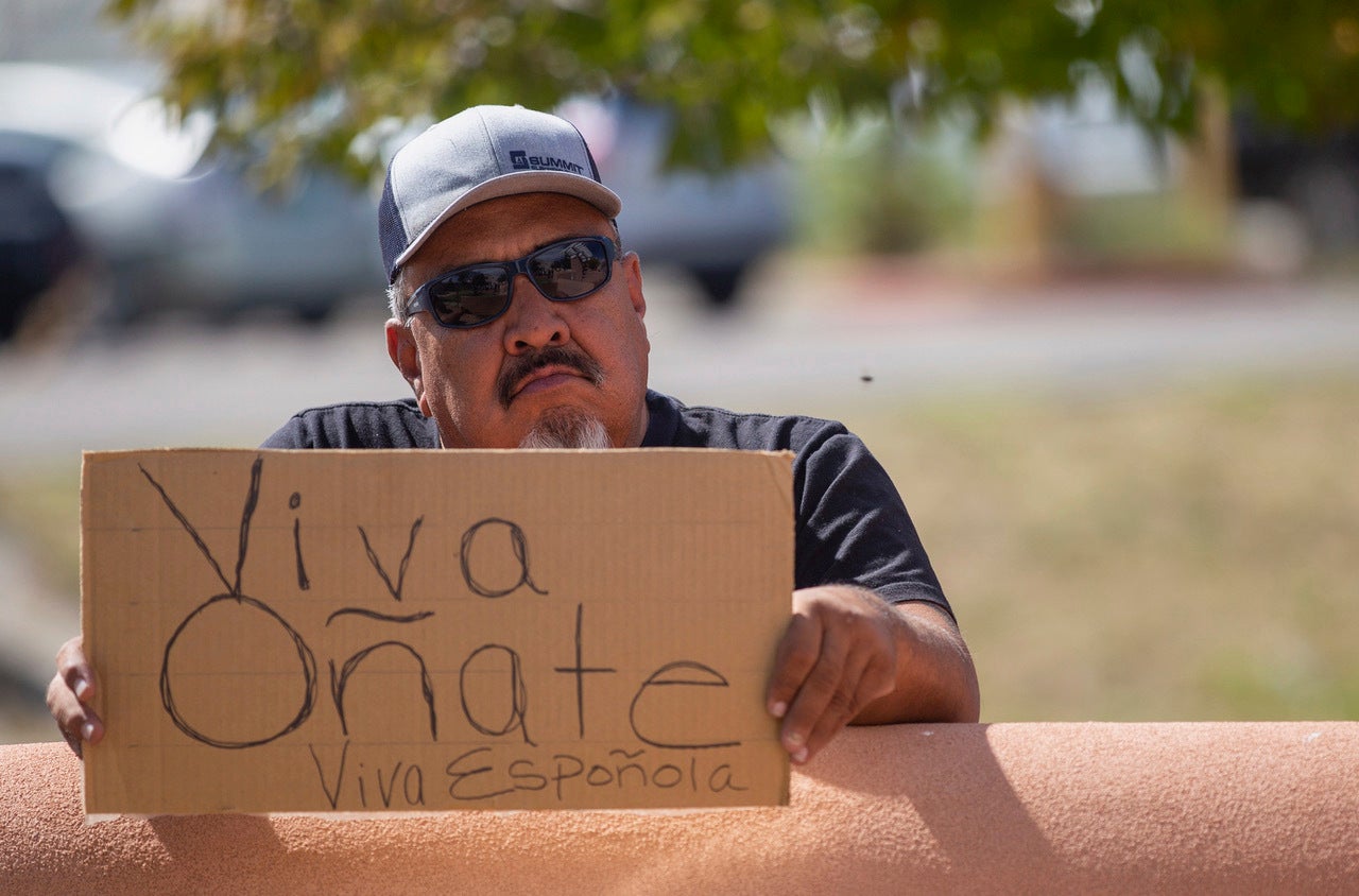 An onlooker holds a “Viva Oñate” sign while demonstrators gather in front of the Rio Arriba County Complex to protest the placing of a statue of a Spanish conquistador