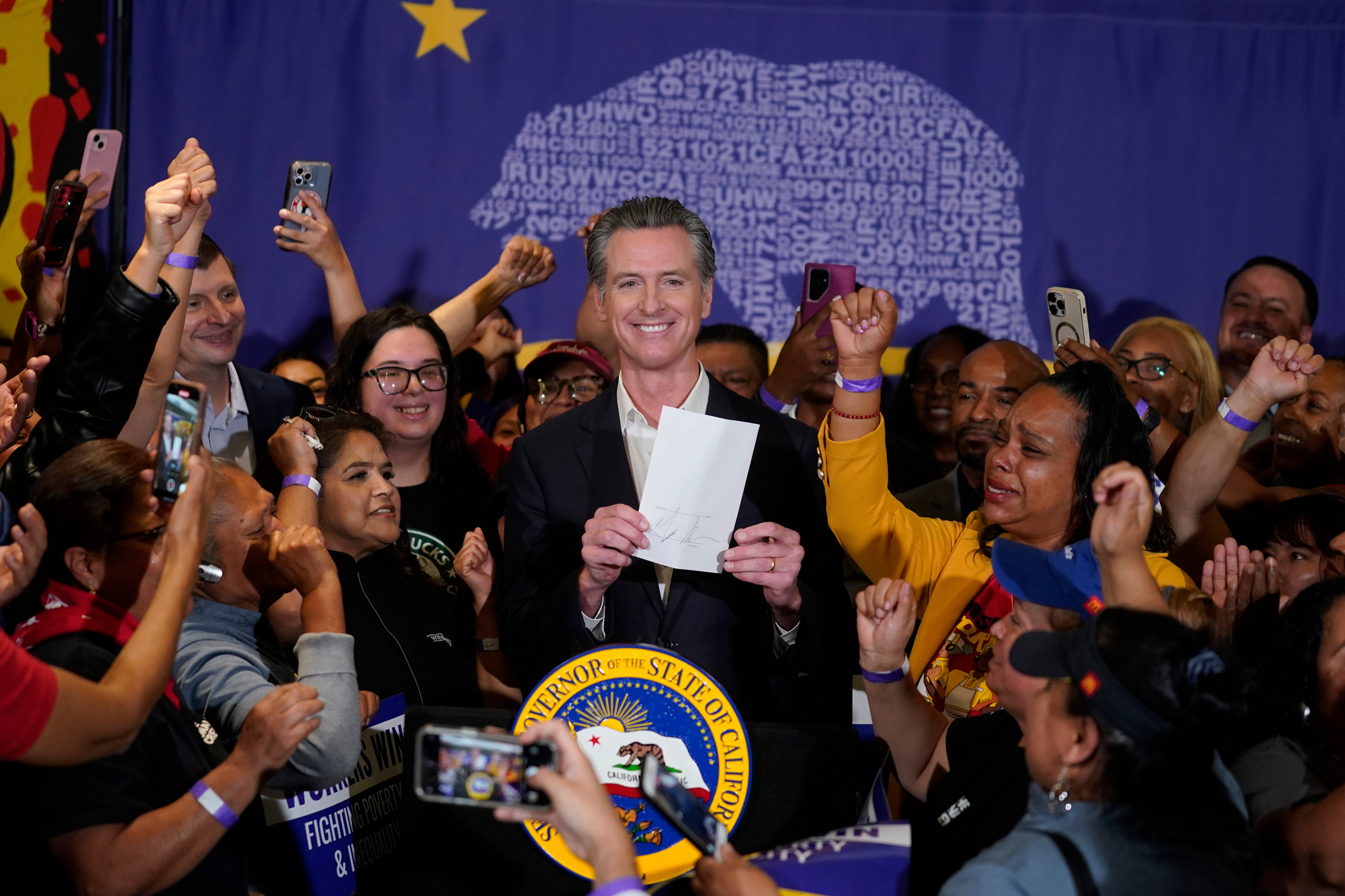 California Gov. Gavin Newsom signs the fast food bill surrounded by fast food workers at the SEIU Local 721 in Los Angeles, on Thursday, Sept. 28, 2023.