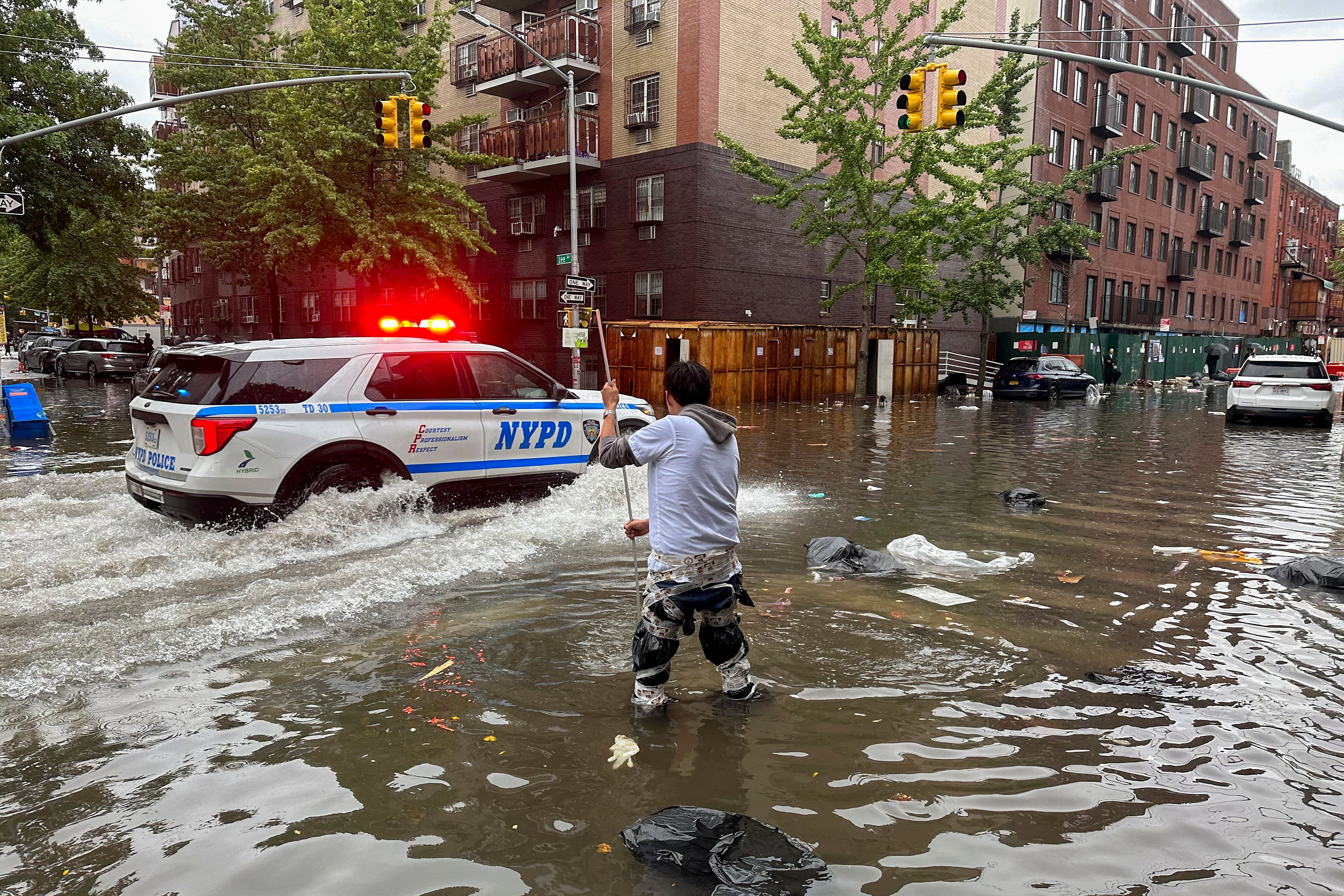 A man works to clear a drain in flood waters in Brooklyn on Friday. A potent rush-hour rainstorm swamped the New York metropolitan area